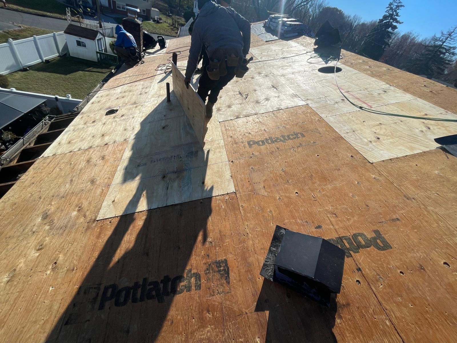 A man is standing on top of a wooden roof.