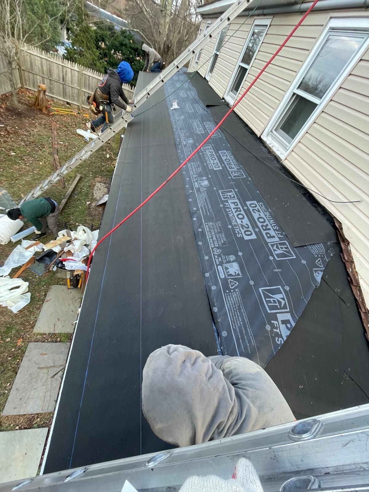 A group of people are working on the roof of a house.