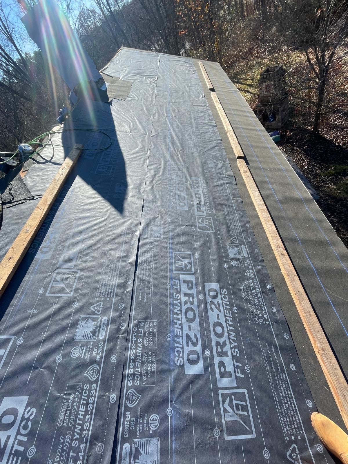 A person is holding a piece of black tarp on top of a roof