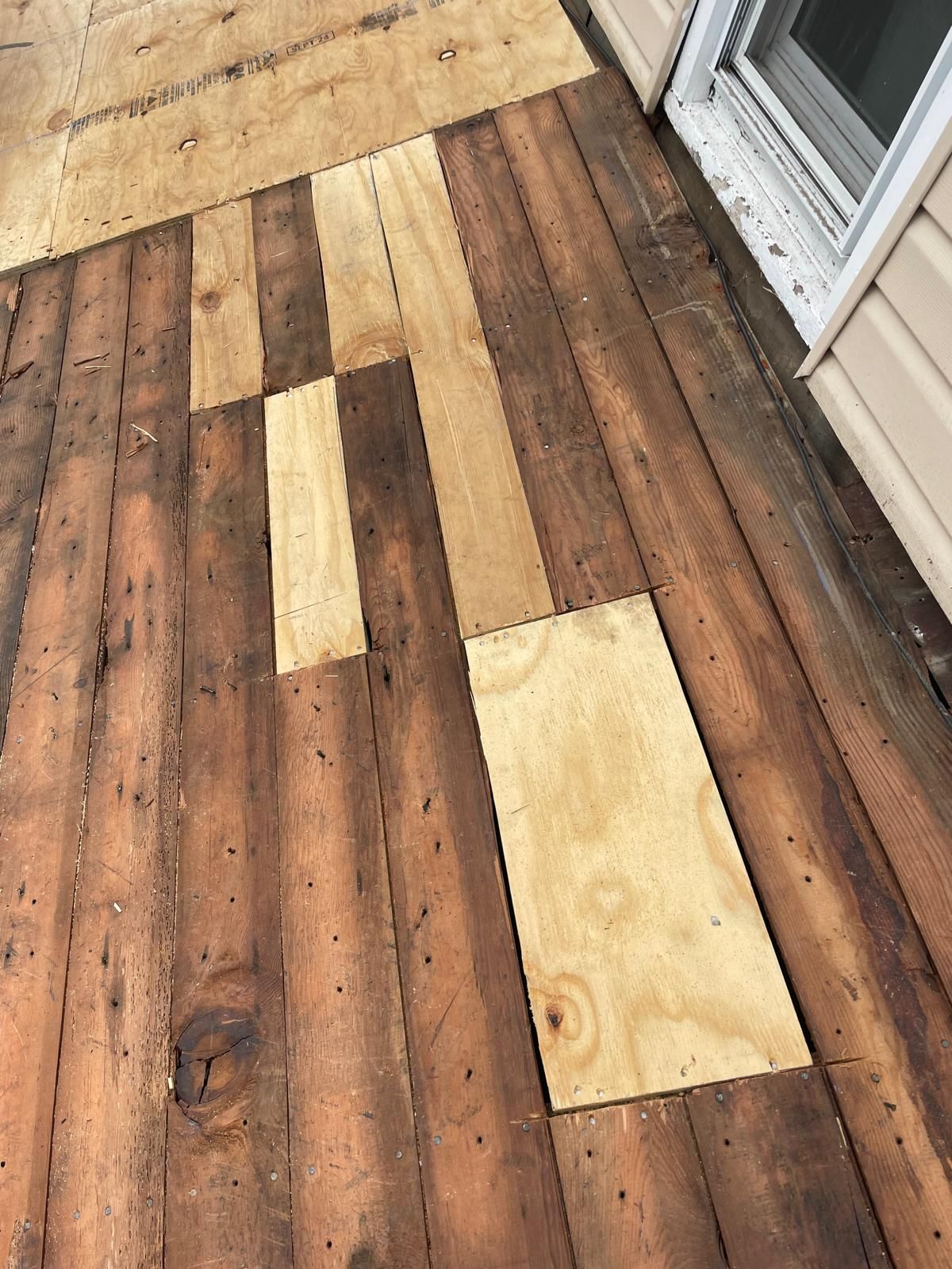 A wooden deck with a few pieces of plywood on it.