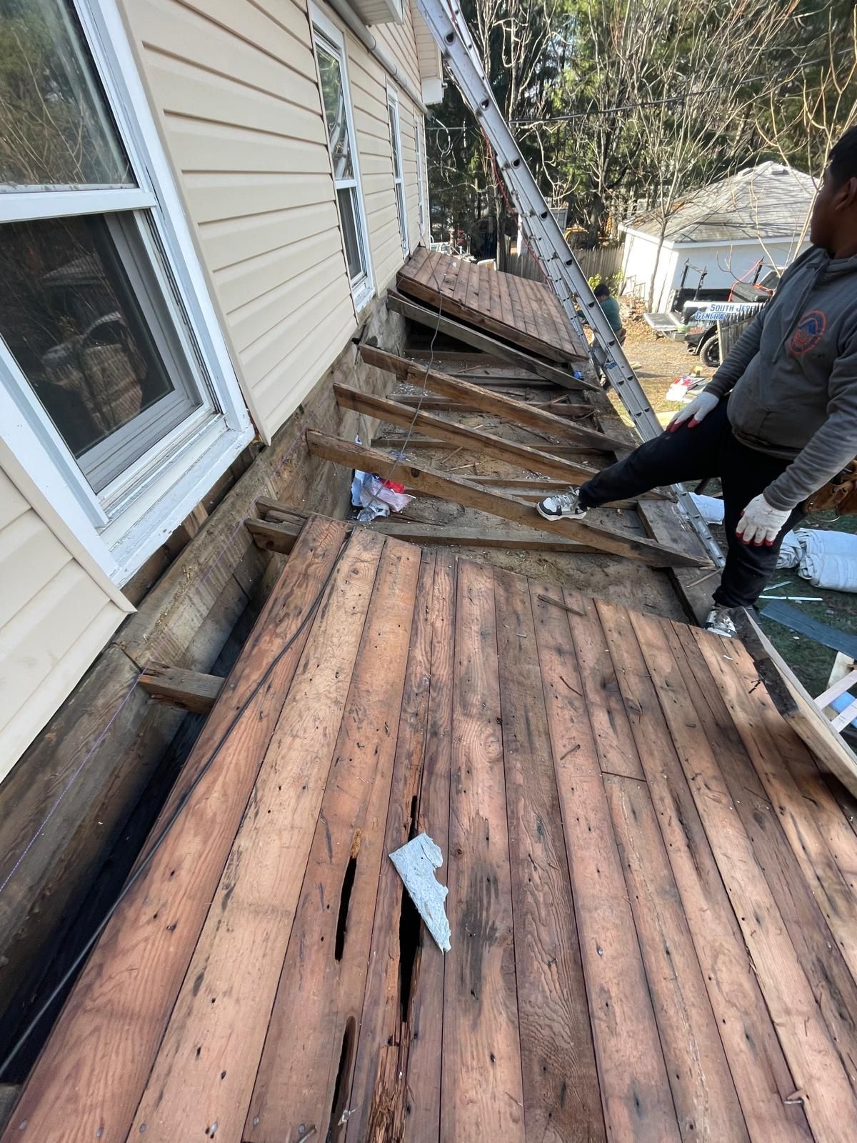 A man is standing on a wooden deck next to a house