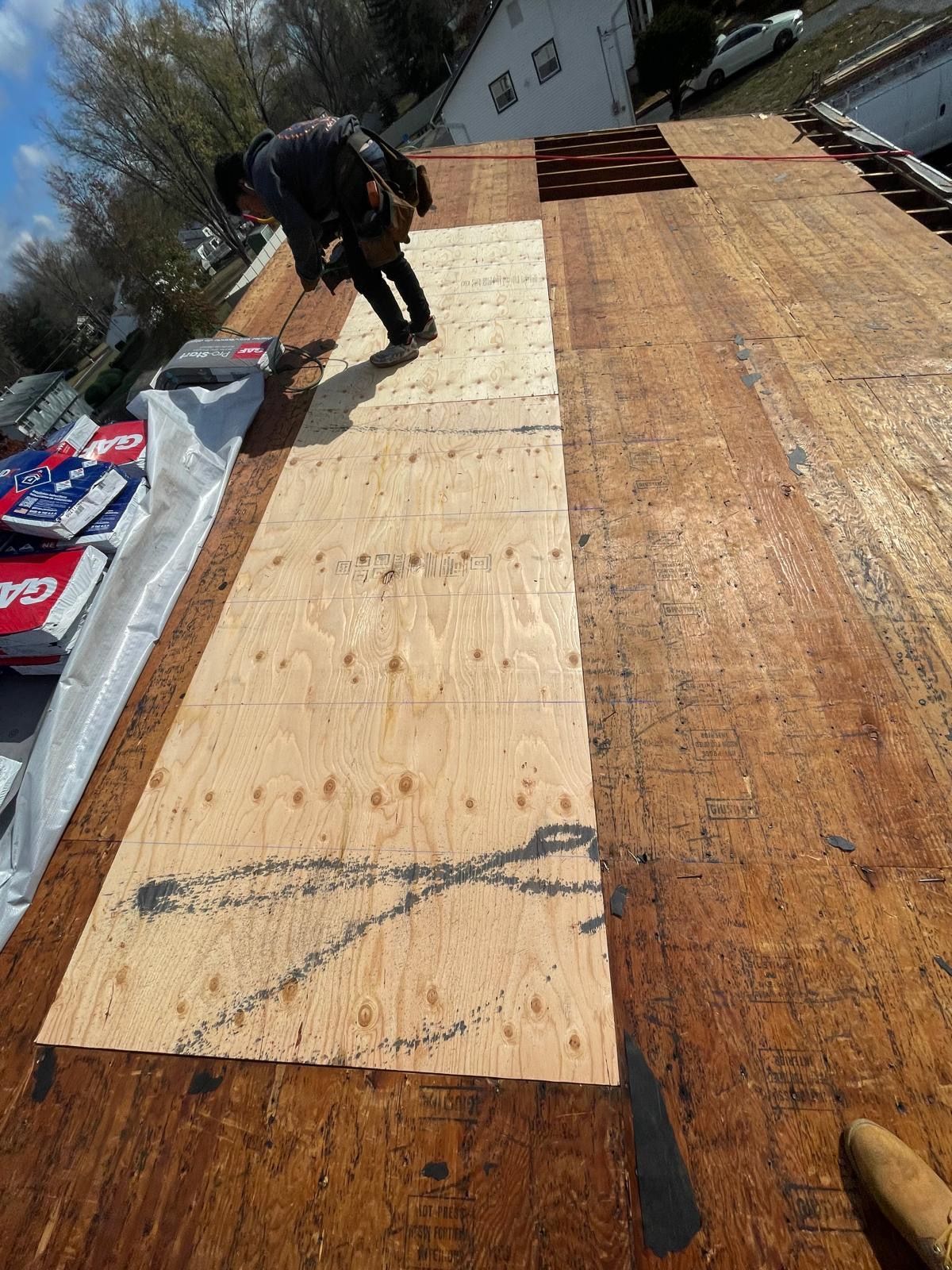 A man is standing on top of a wooden roof.