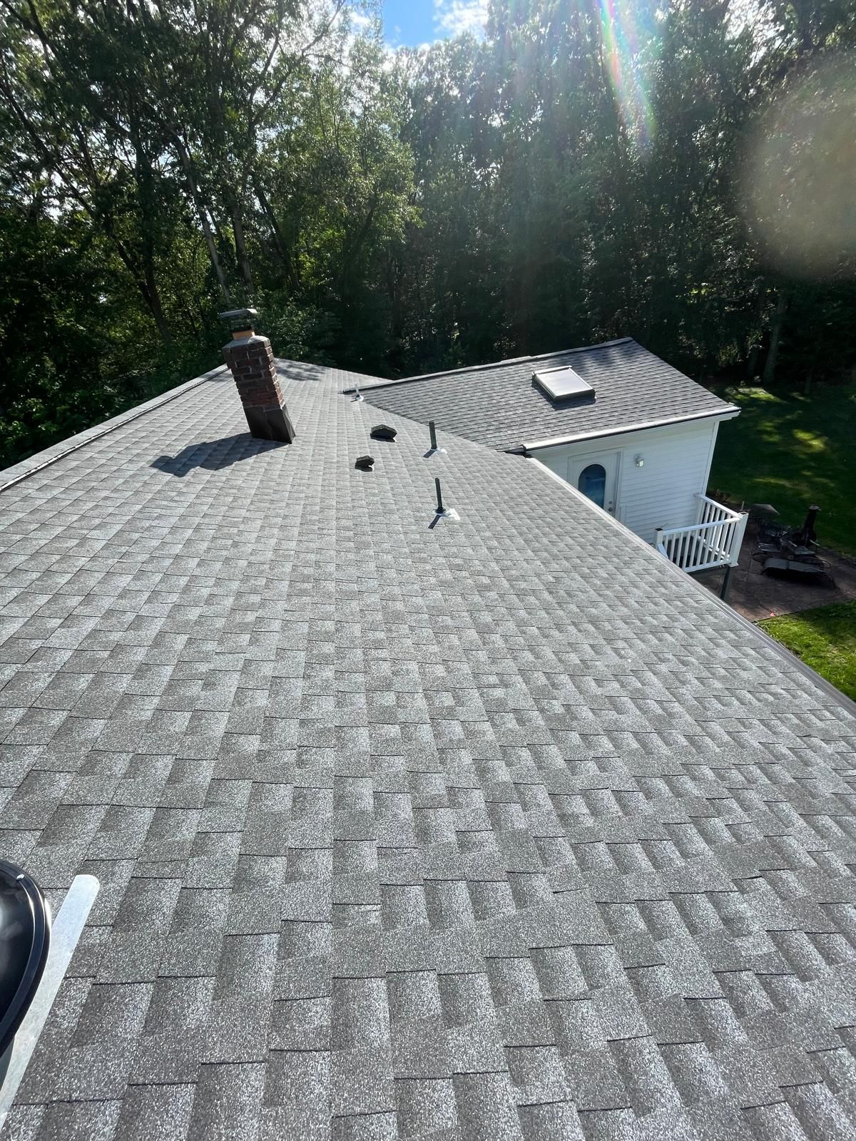 A roof with a chimney on top of it and trees in the background.