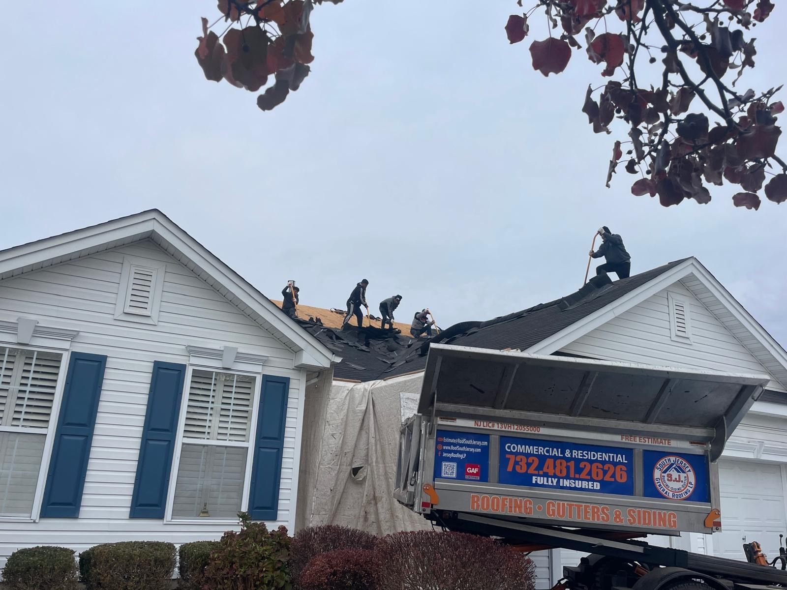 A group of people are working on the roof of a house.