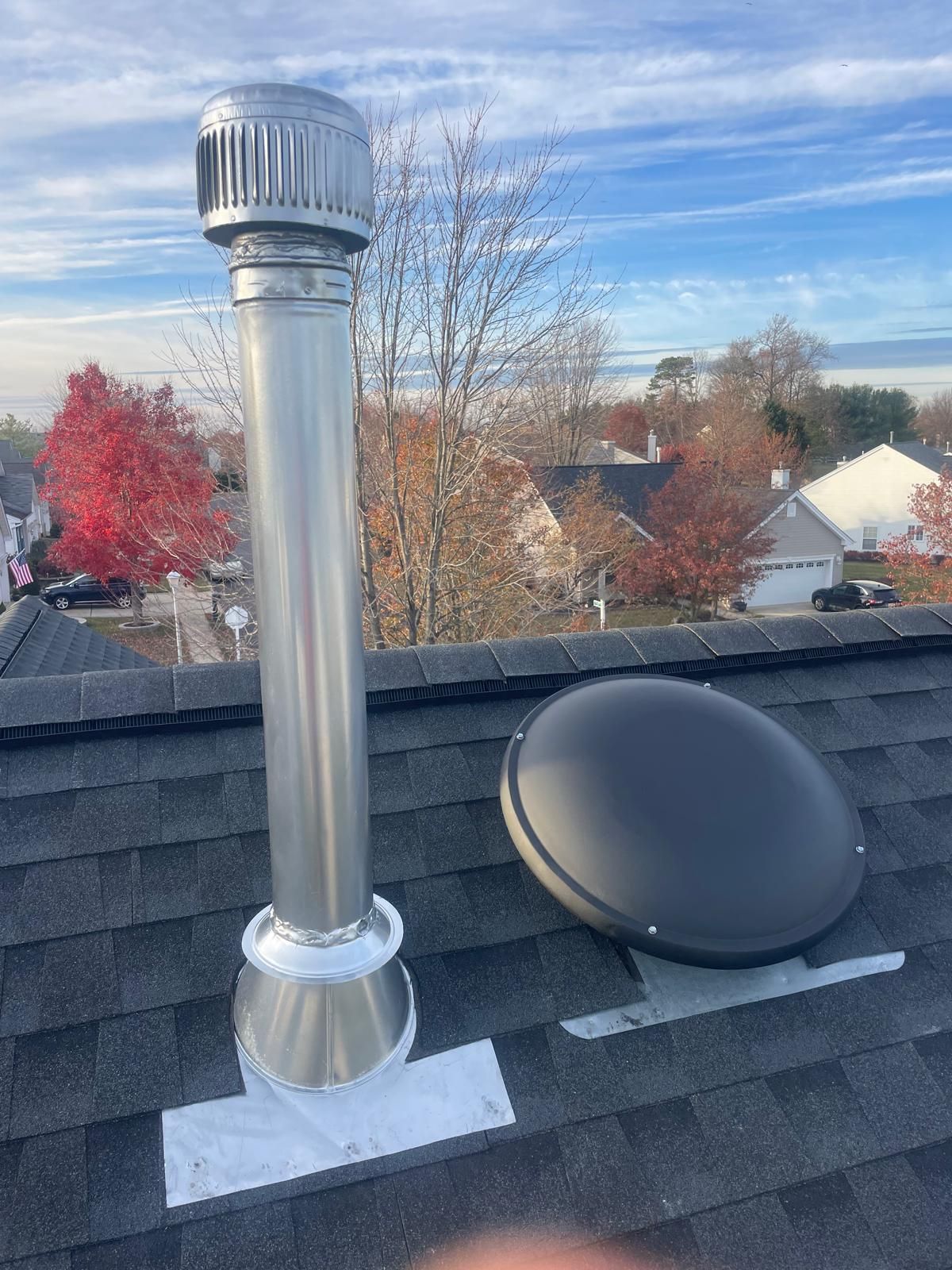 A stainless steel chimney is sitting on top of a roof.
