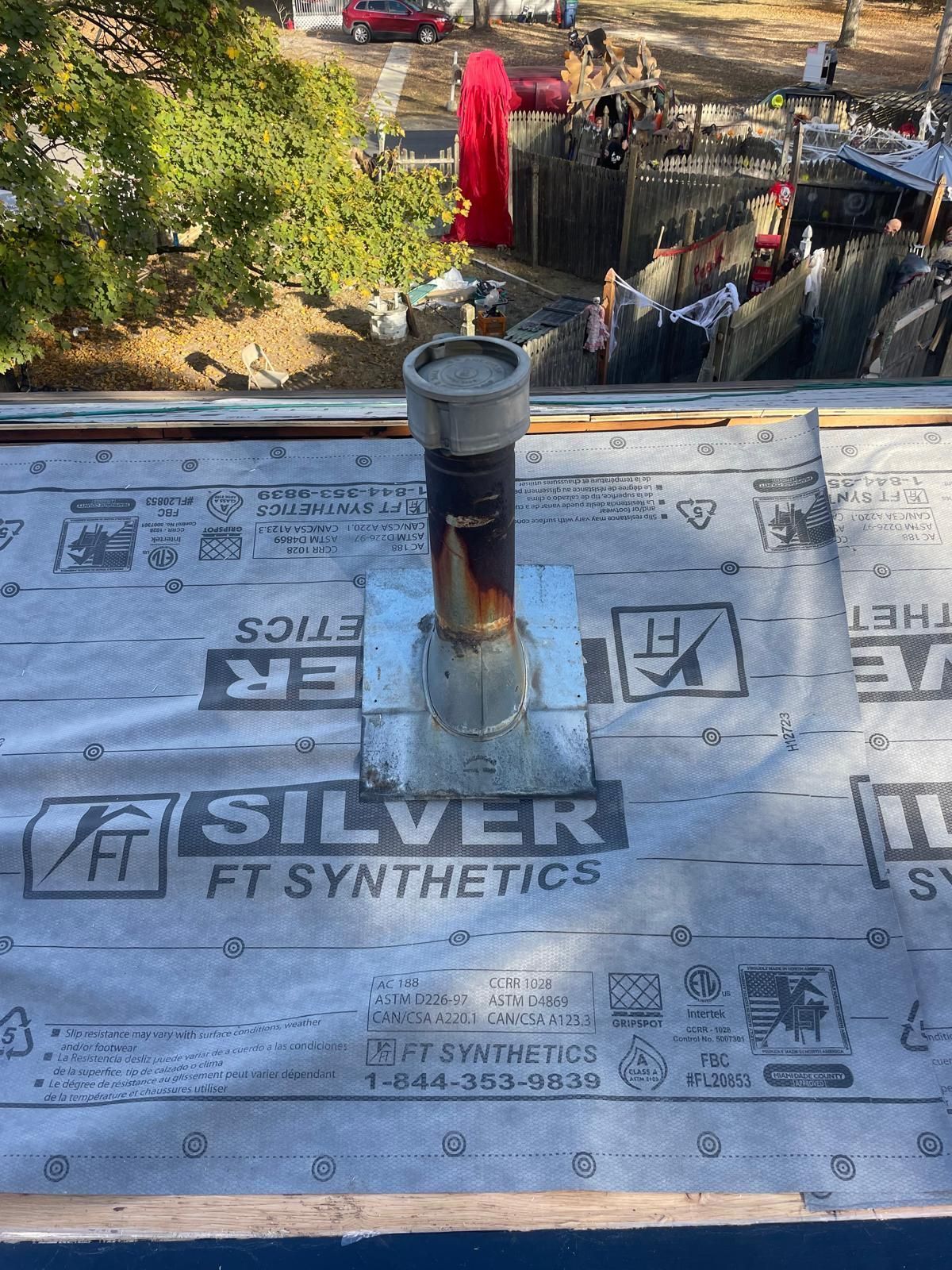 A pipe is sitting on top of a roof covered in silver ft synthetics.