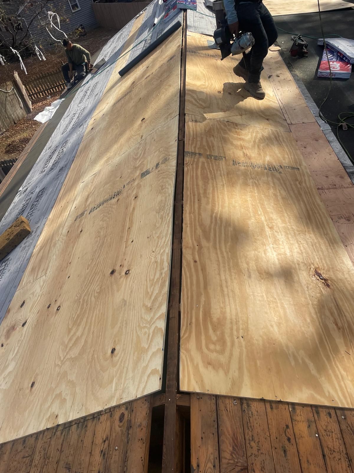 A person is standing on top of a wooden roof.
