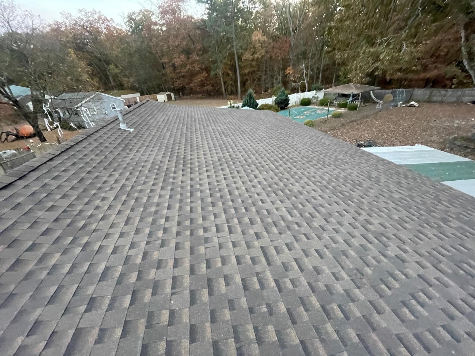 The roof of a house with a swimming pool in the background.