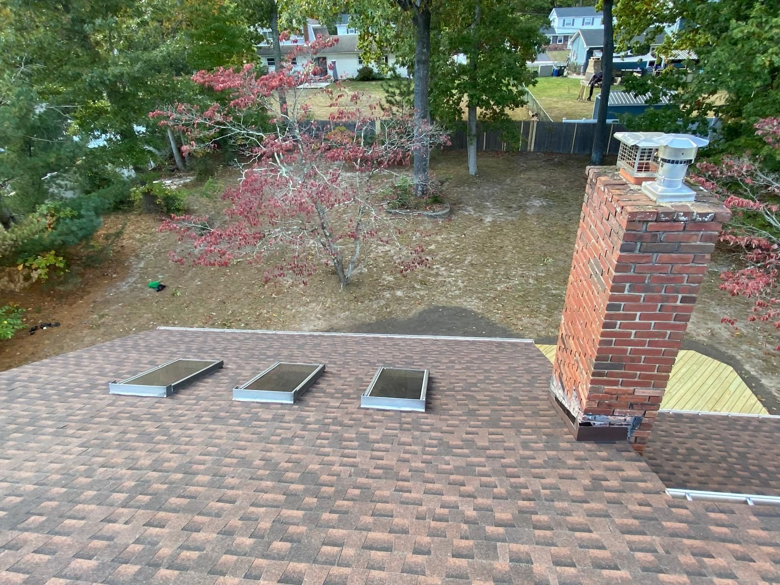 A roof with a brick chimney and skylights on it
