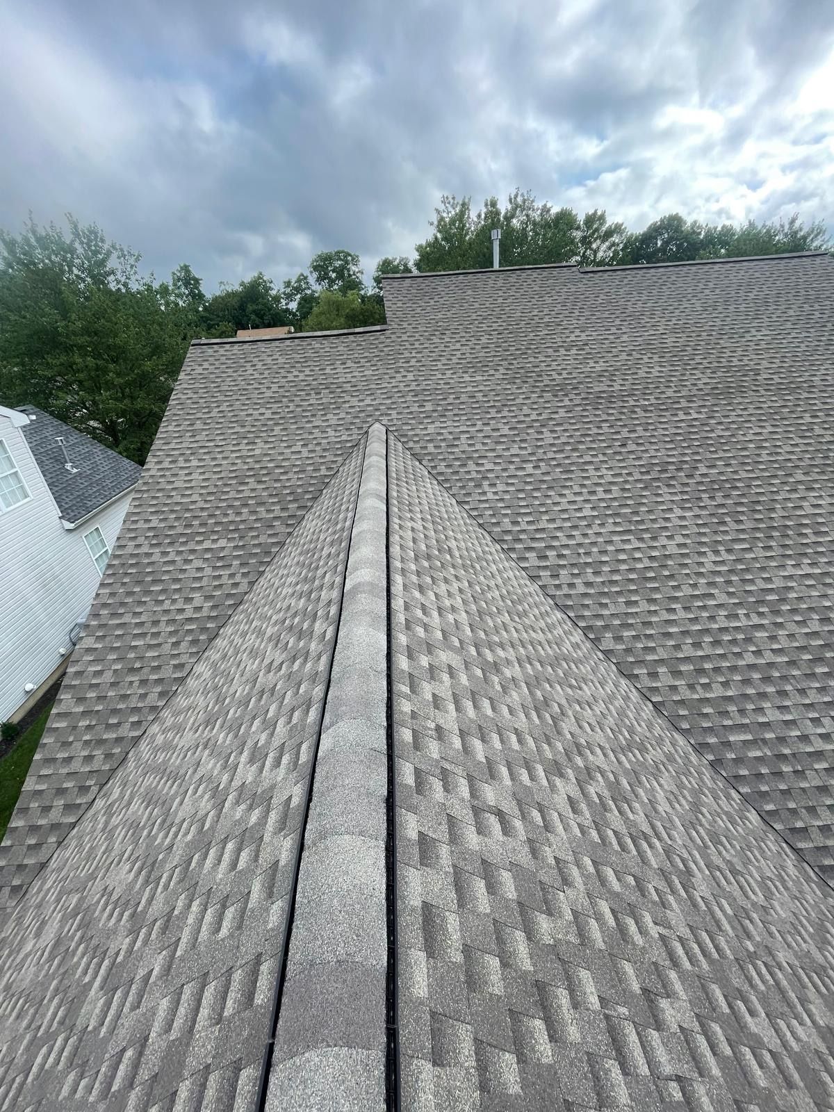 A roof with a lot of shingles on it and trees in the background.
