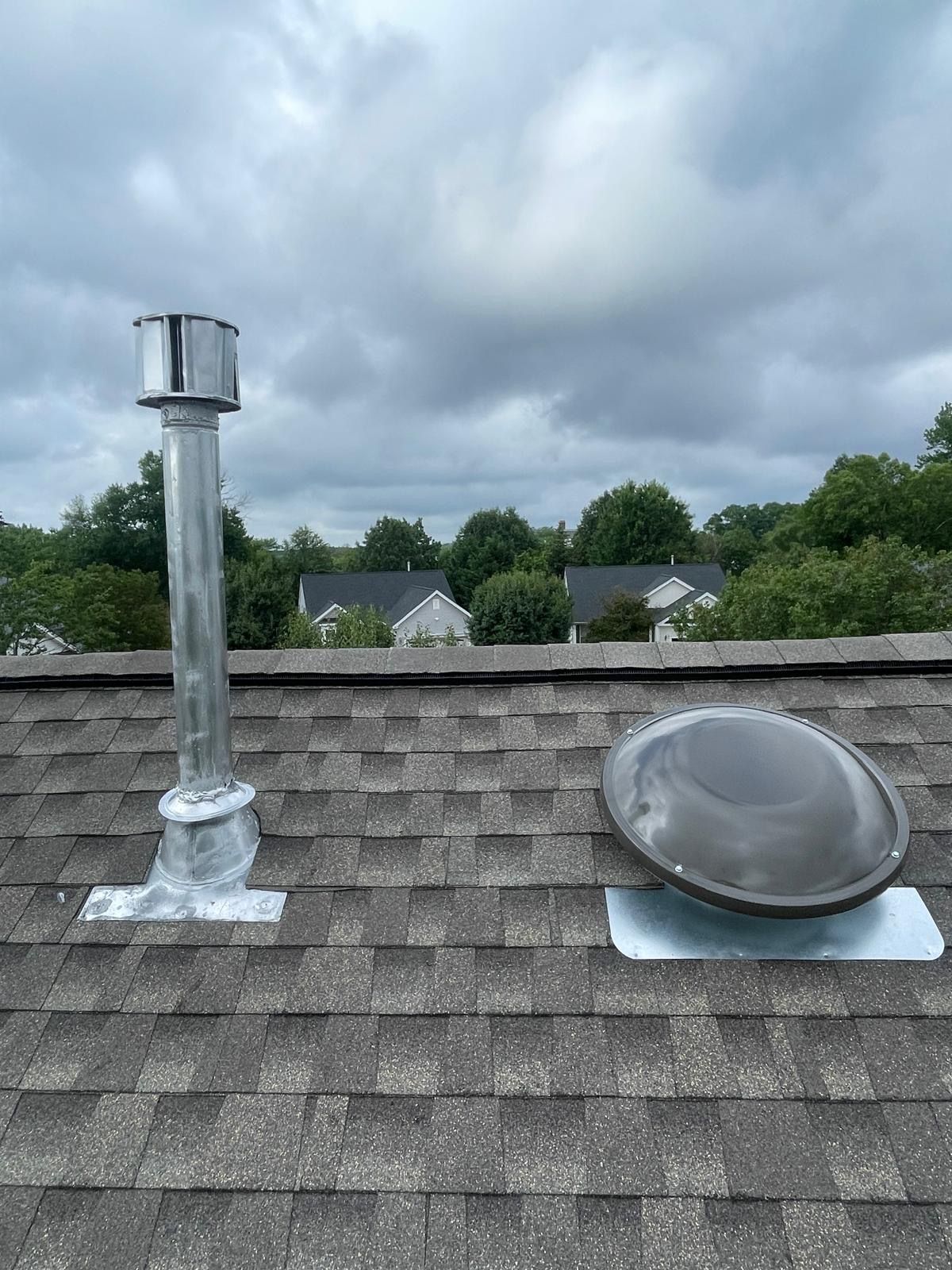 A roof with a chimney and a skylight on it.