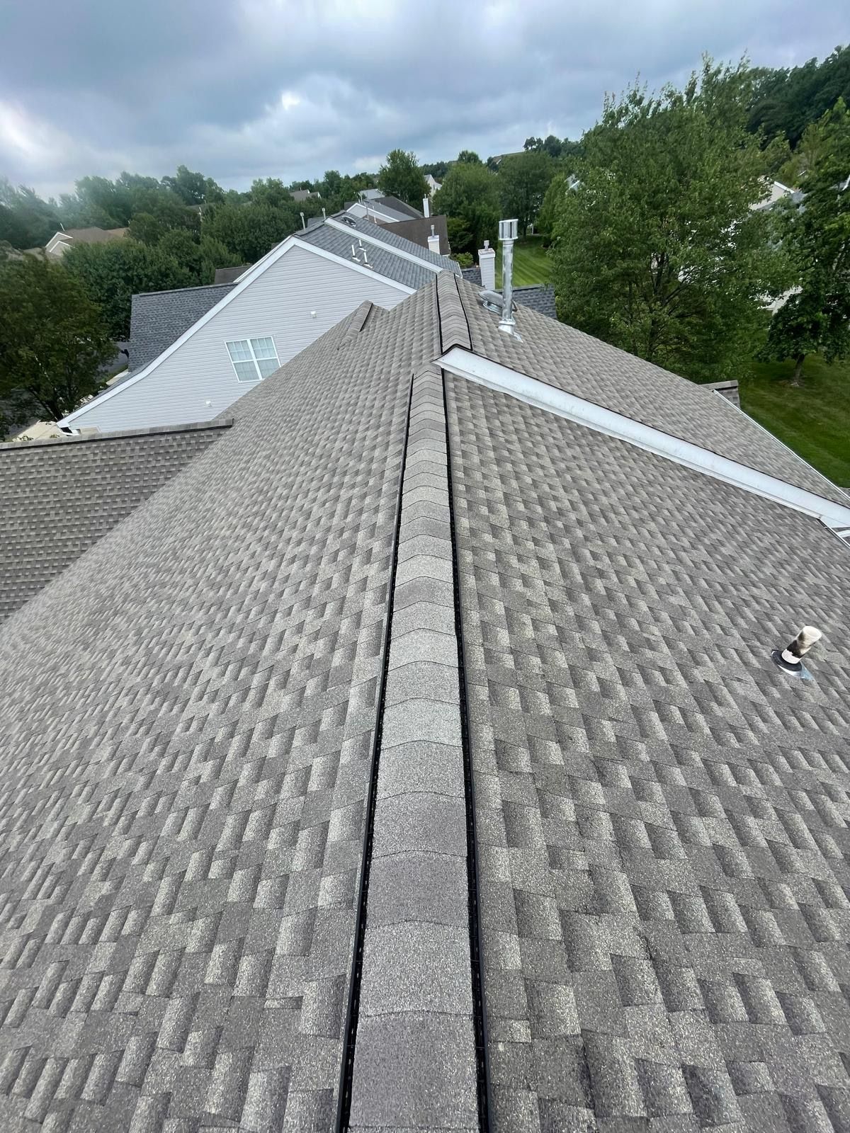 A roof with a lot of shingles on it and trees in the background.