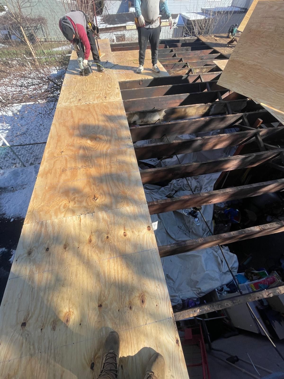A group of people are working on a wooden roof.