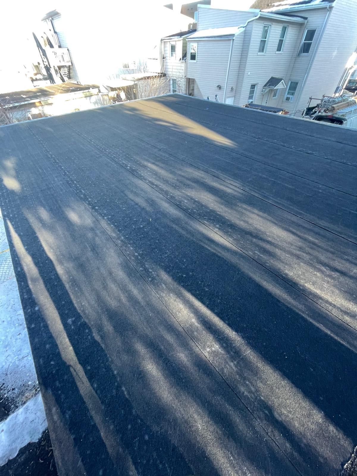 A black roof with a white building in the background.