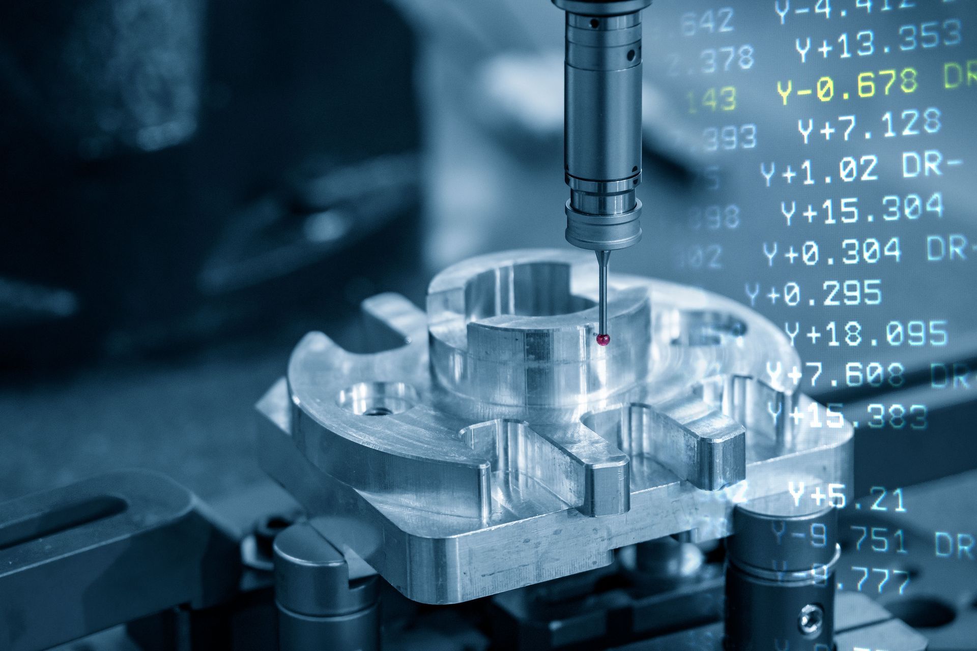 A metal part being measured by a CMM machine. White data overlays on the image.
