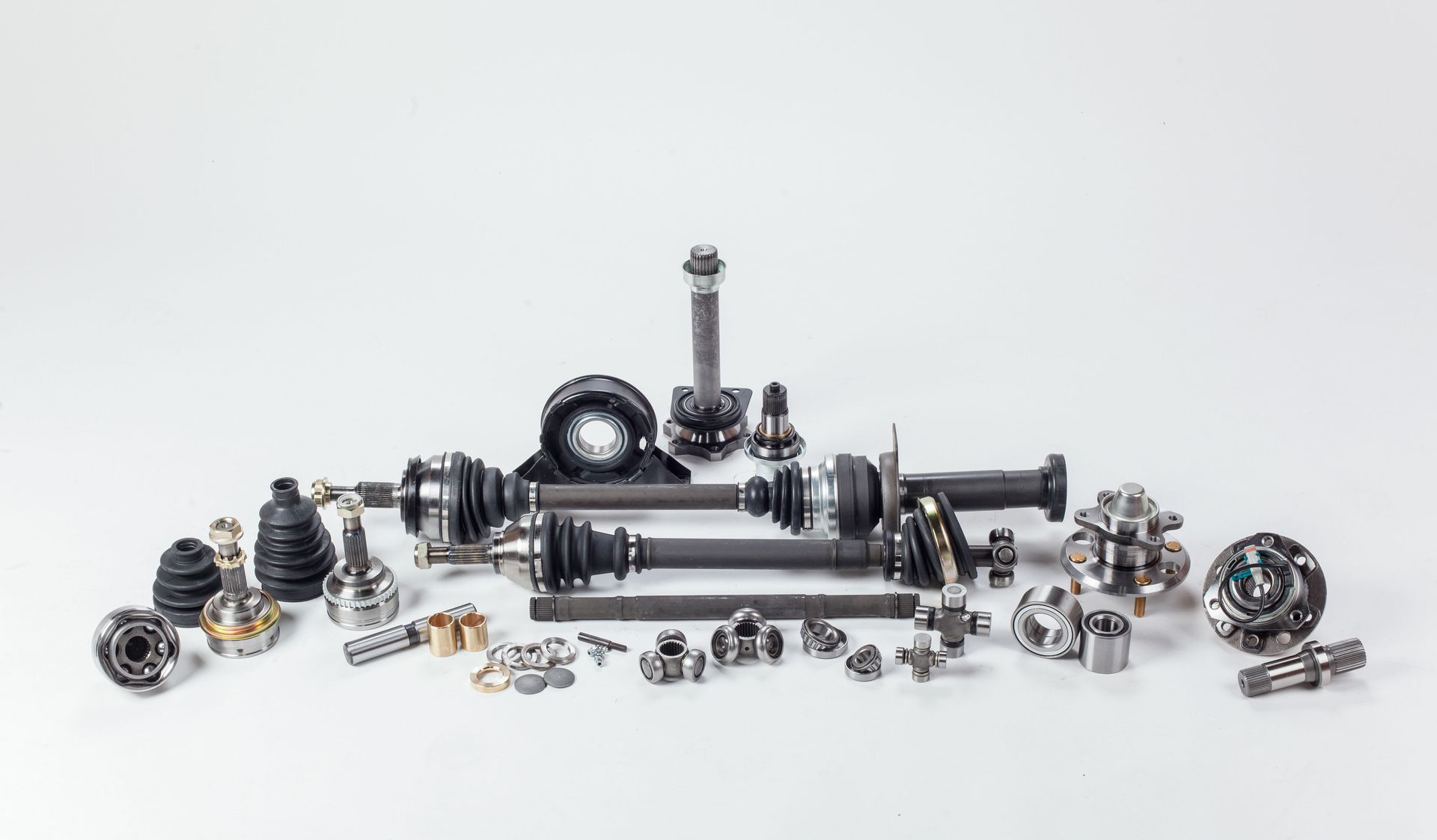 Car axle parts laid out on a white surface, featuring various metal components and black rubber boots.