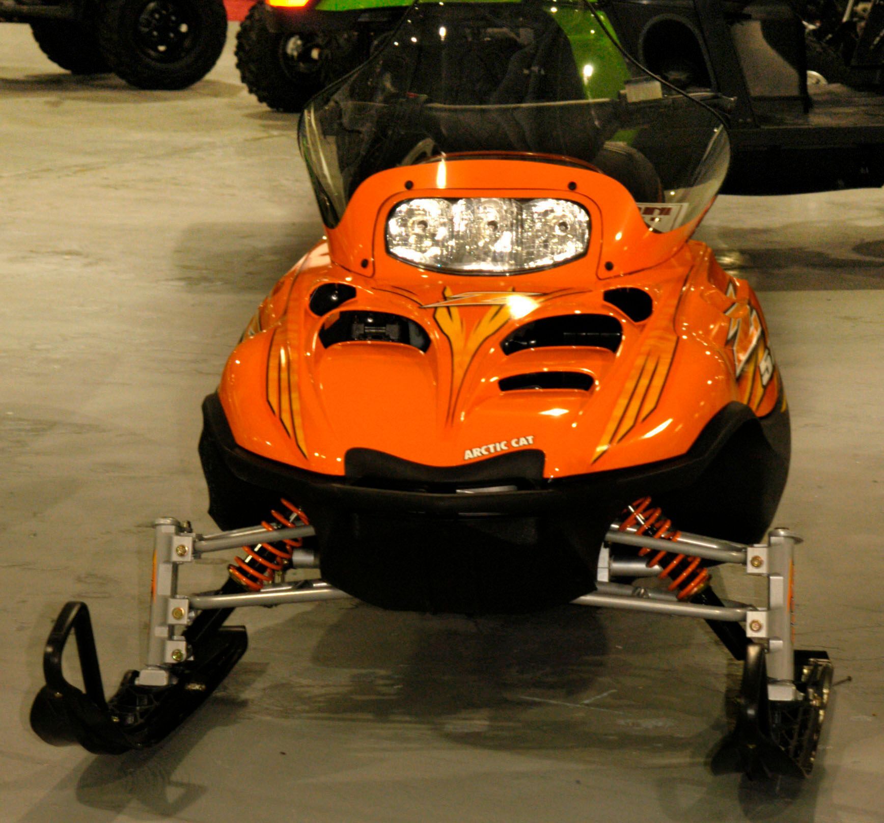 Orange Arctic Cat snowmobile on a concrete floor.