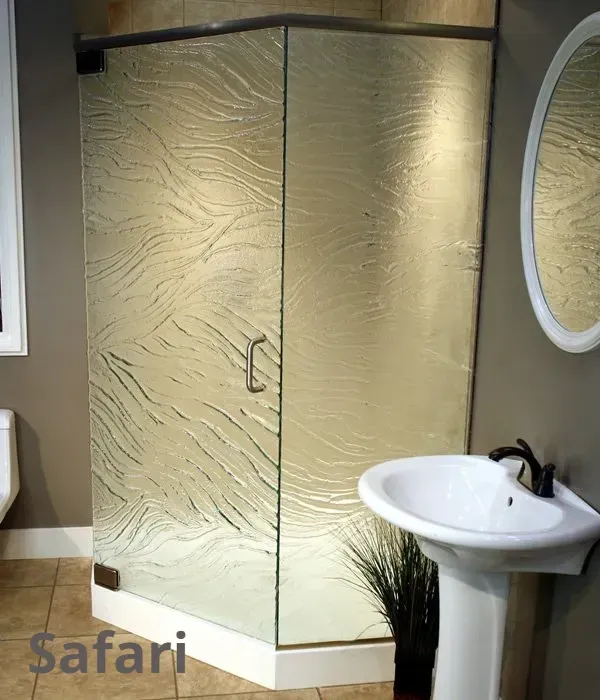 A corner shower stall with textured, patterned glass doors, situated in a bathroom next to a white pedestal sink.