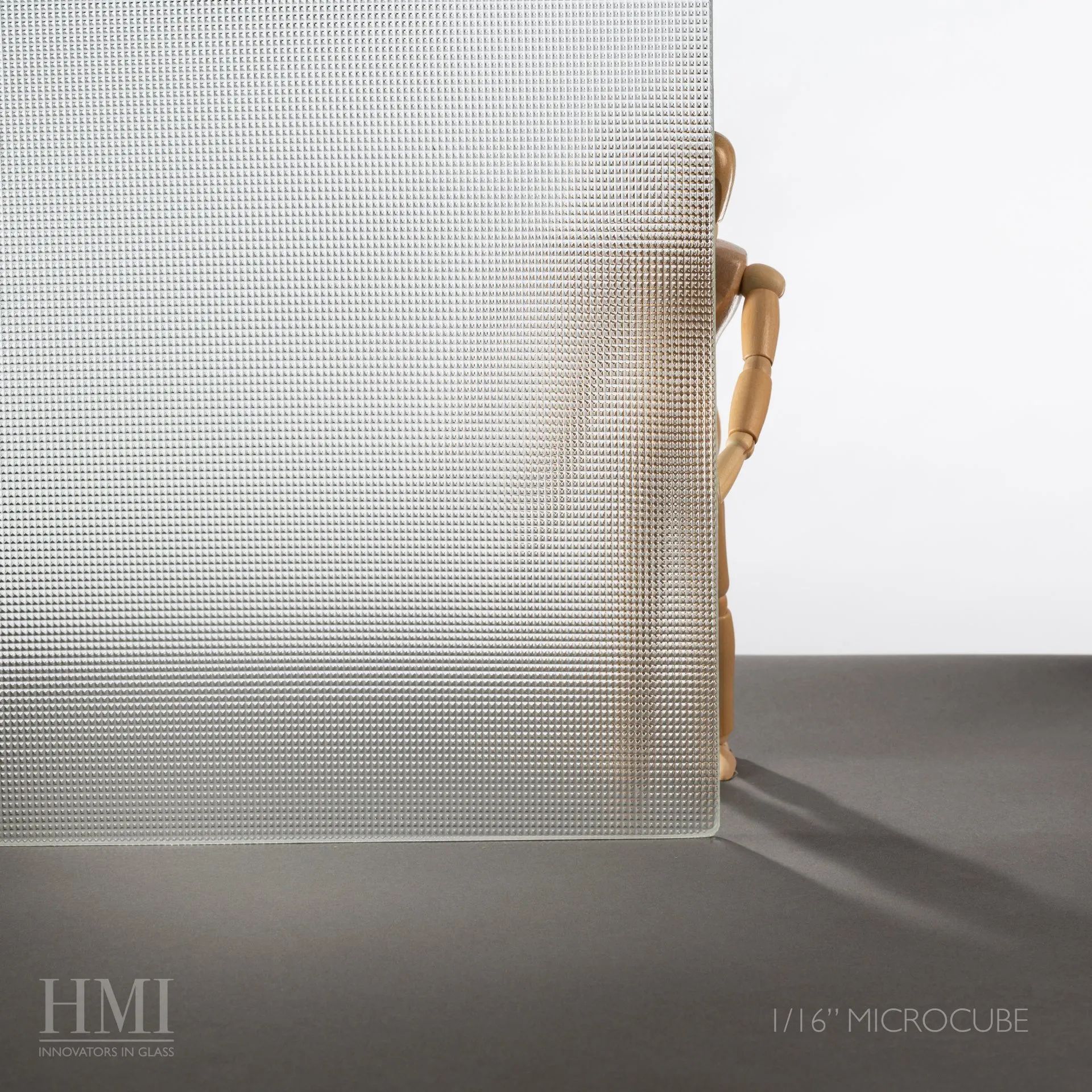 A sheet of textured, gridded Microcube glass standing in front of an artist’s wooden mannequin figure.