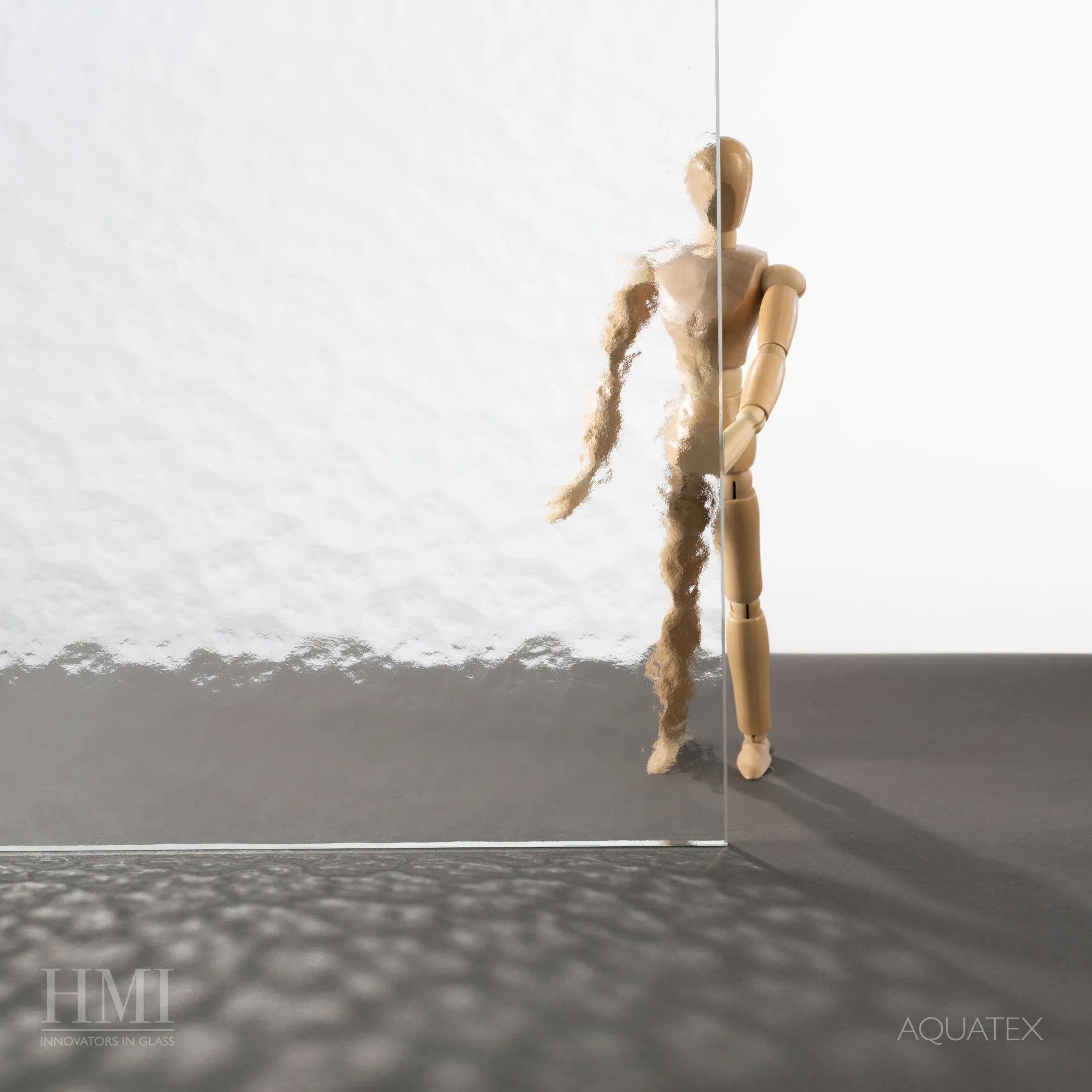 A wooden mannequin stands behind textured glass, showing clear visibility on the right and distorted views on the left.