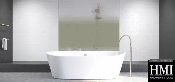 A modern bathroom features a white freestanding bathtub against a wall with white tile and a green glass splashback.