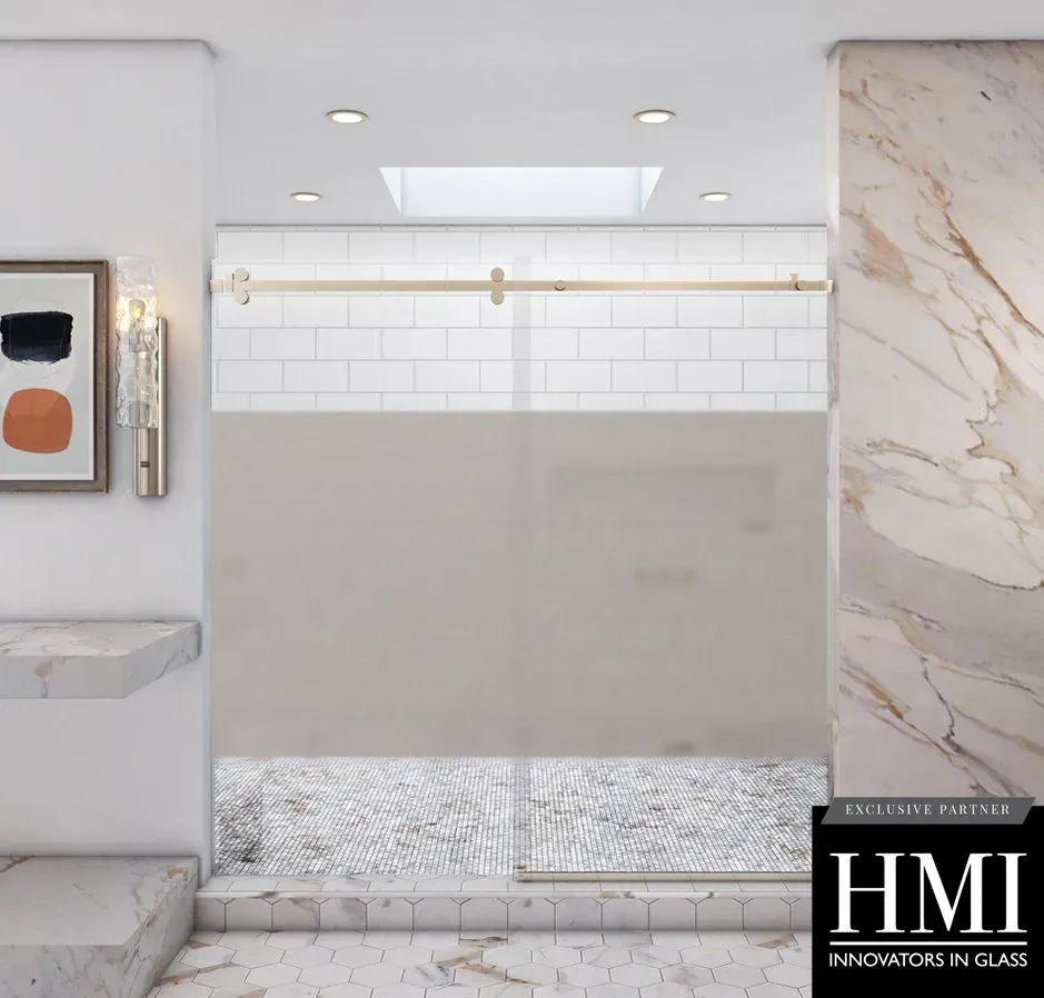 A modern glass shower door with gold hardware, frosted paneling, and white tile, situated in a marble bathroom.