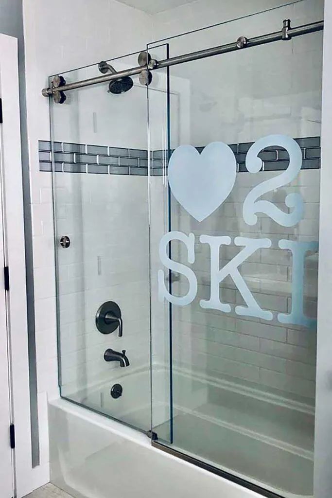 A modern bathtub shower with glass sliding doors featuring a frosted