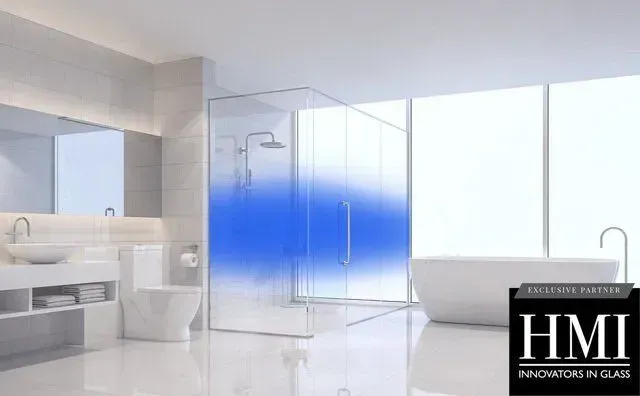 A modern bathroom featuring a walk-in glass shower with a blue gradient privacy film, a white tub, and a vanity.