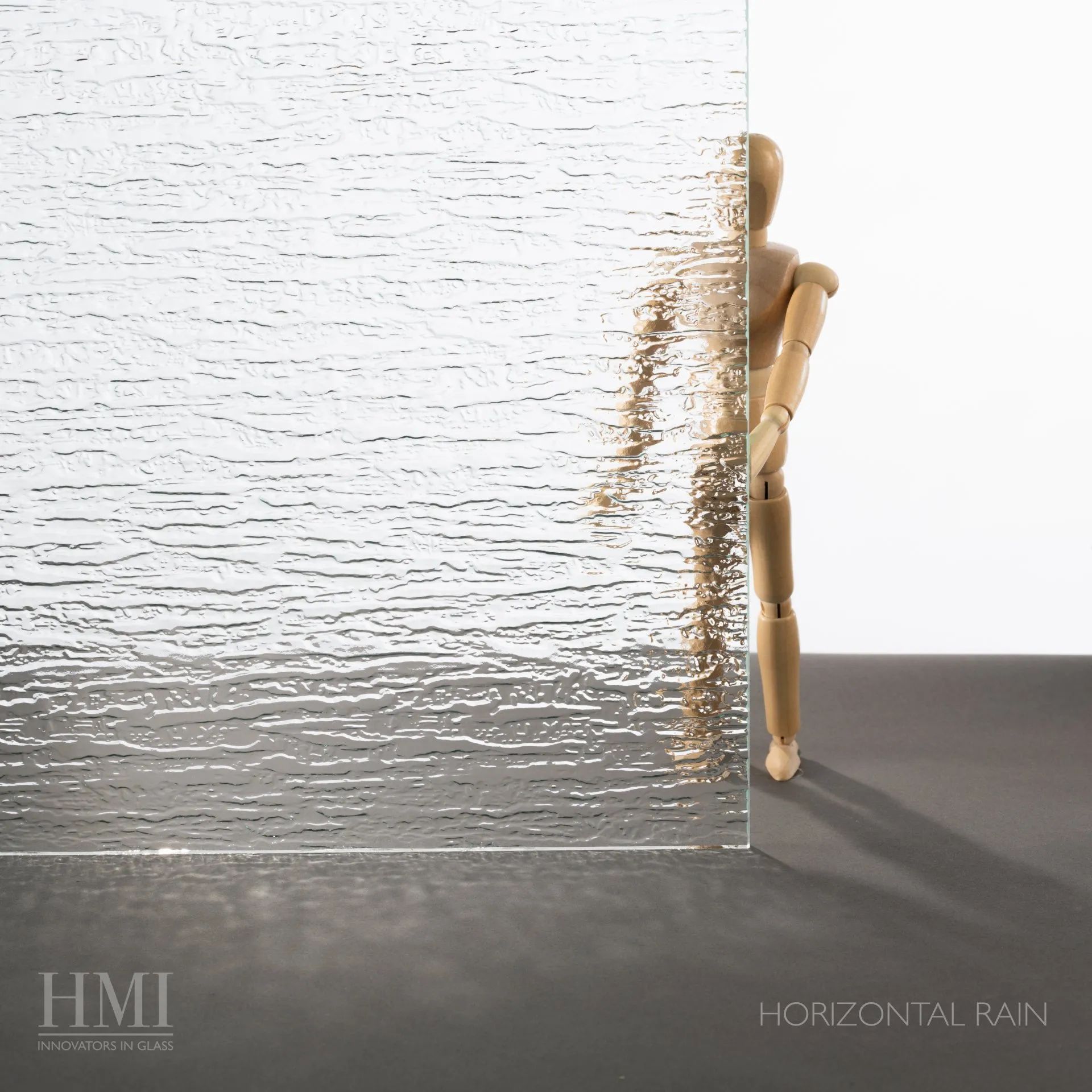A pane of textured Horizontal Rain pattern glass obscuring a small wooden mannequin figure.