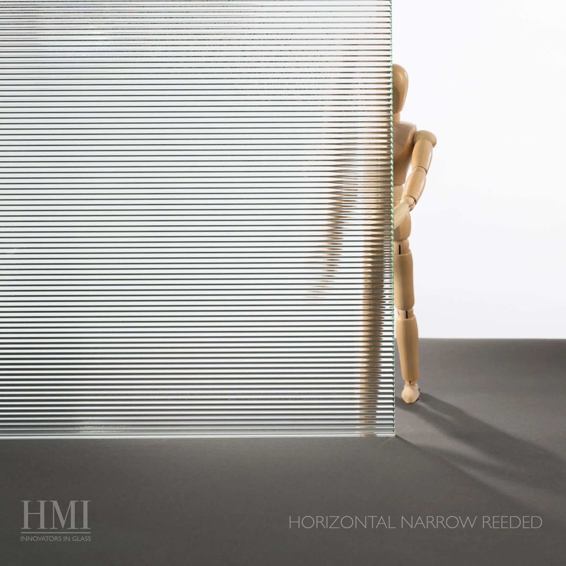 A clear glass panel with fine horizontal lines obscuring a wooden mannequin figure against a white background.