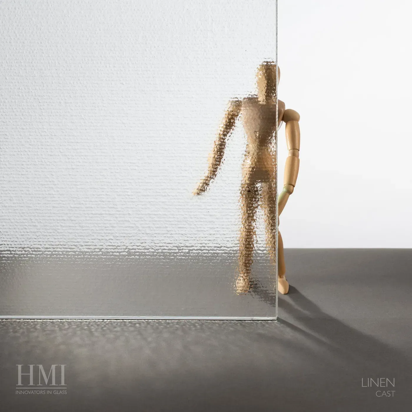 A wooden artist's mannequin stands behind a sheet of textured