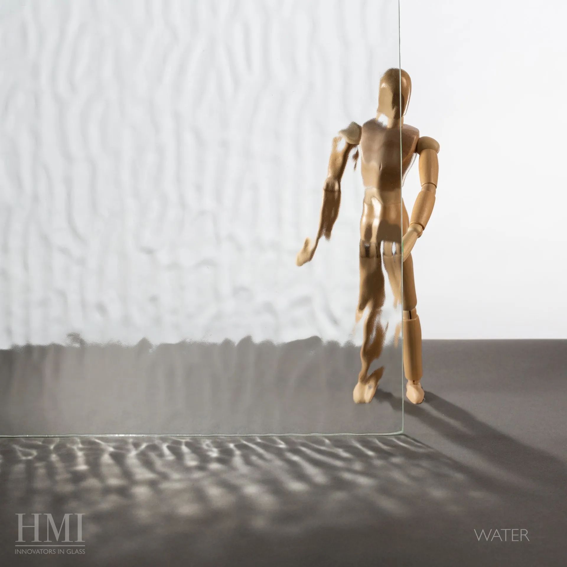 A wooden artist's mannequin stands behind a sheet of textured