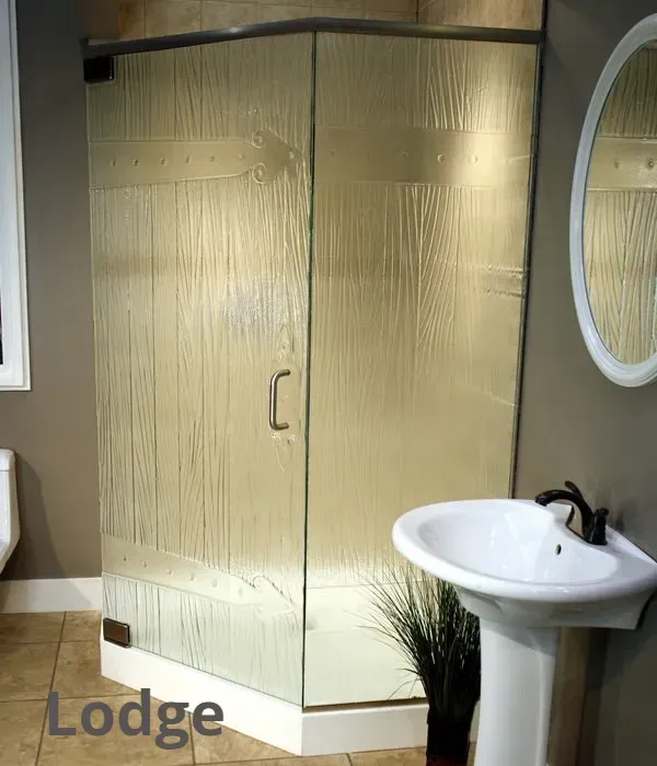 A corner shower stall with textured glass, wood-patterned accents, and a pedestal sink in a neutral-toned bathroom.