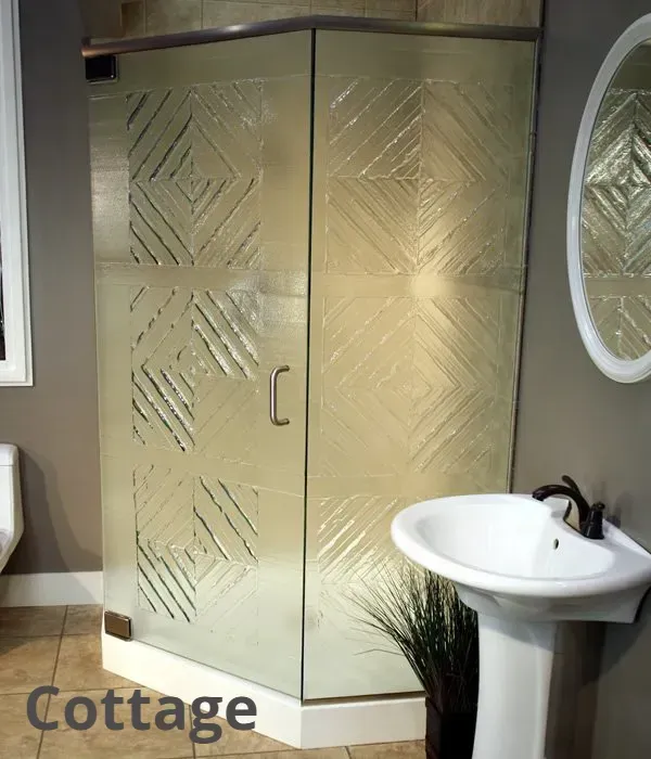 A corner shower stall with patterned glass doors next to a white pedestal sink in a neutral-toned bathroom.