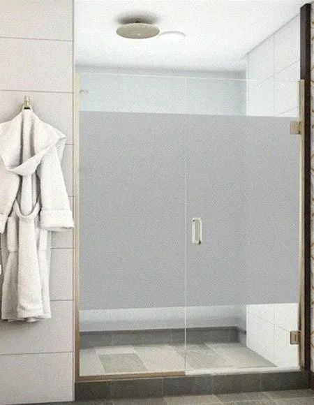 A glass shower door with a frosted privacy panel in a modern bathroom, with a white bathrobe hanging on a nearby wall.