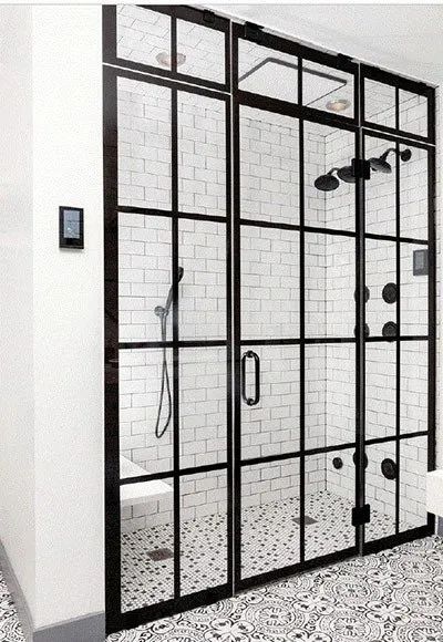 Modern shower stall with a black grid-frame glass door, white subway tile walls, and patterned tile floor.