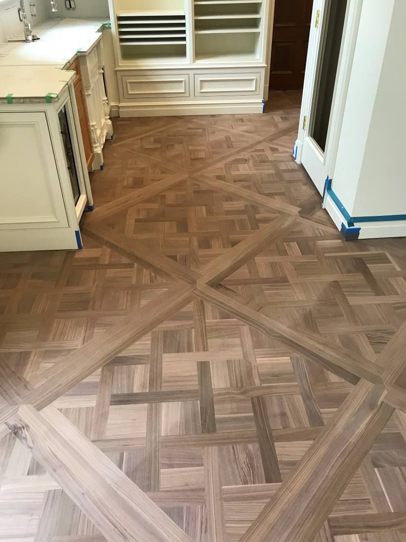 Hardwood floor with decorative border, alongside a chair, candles, and curtain.