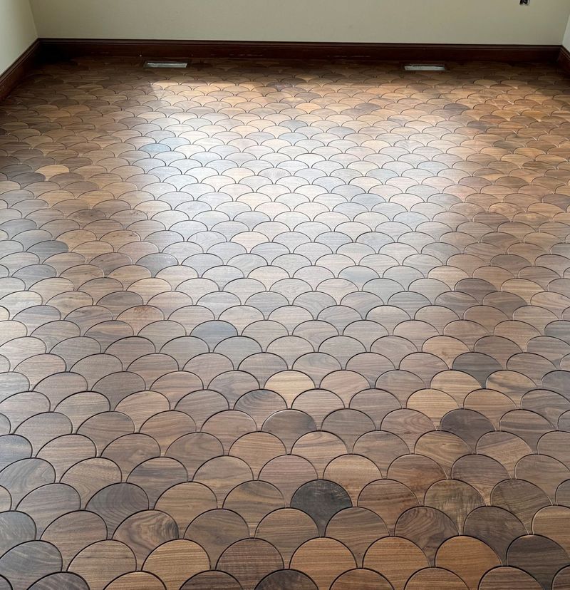 Wooden floor with a scalloped pattern, brown tones, and light reflections.