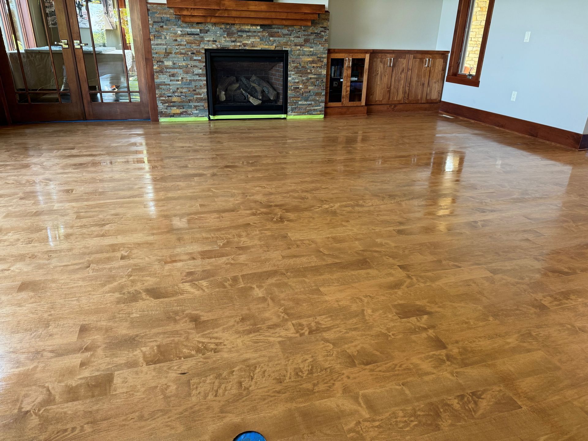 Shiny gold epoxy floor in a living room with a fireplace and wooden trim.