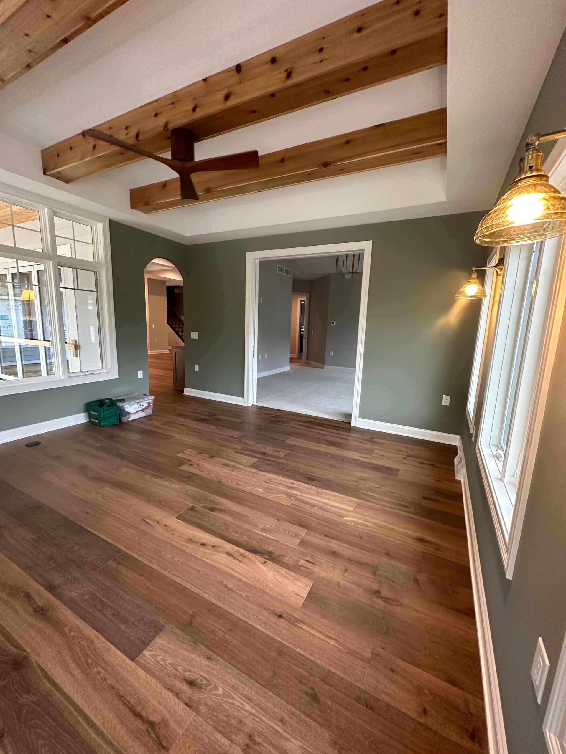 Room with wood floor, green walls, exposed wooden beams, and a doorway.