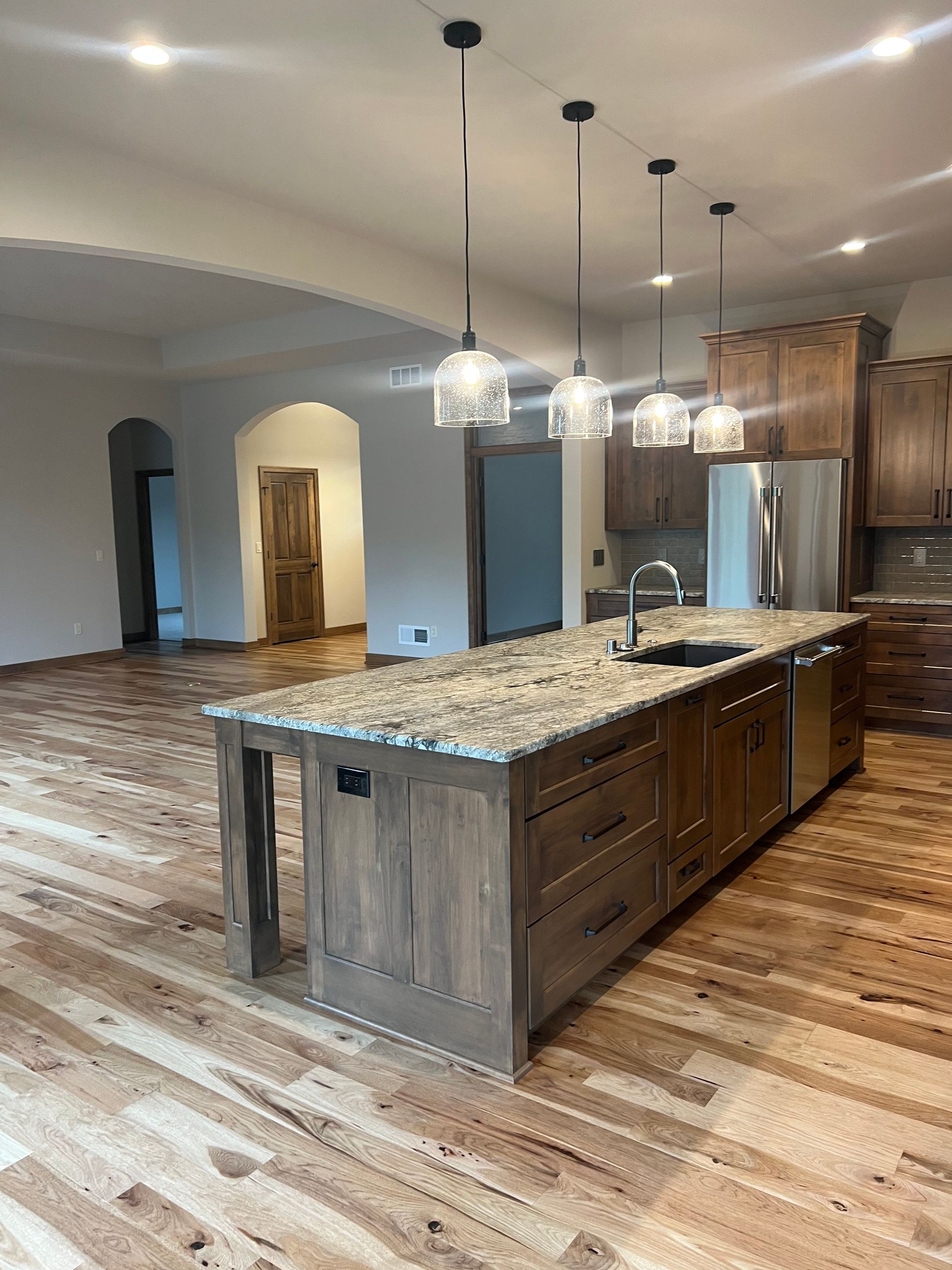 Kitchen with a wood island, granite countertop, and pendant lights. Brown cabinets and stainless steel appliances.