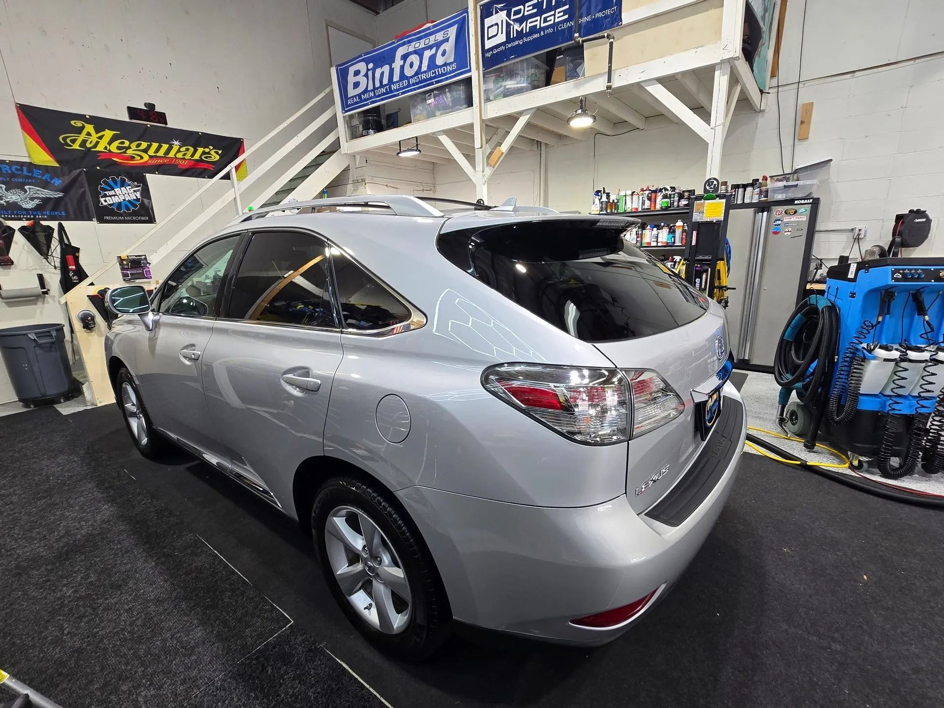 A silver Lexus RX SUV parked at an angle inside a well-lit automotive garage.