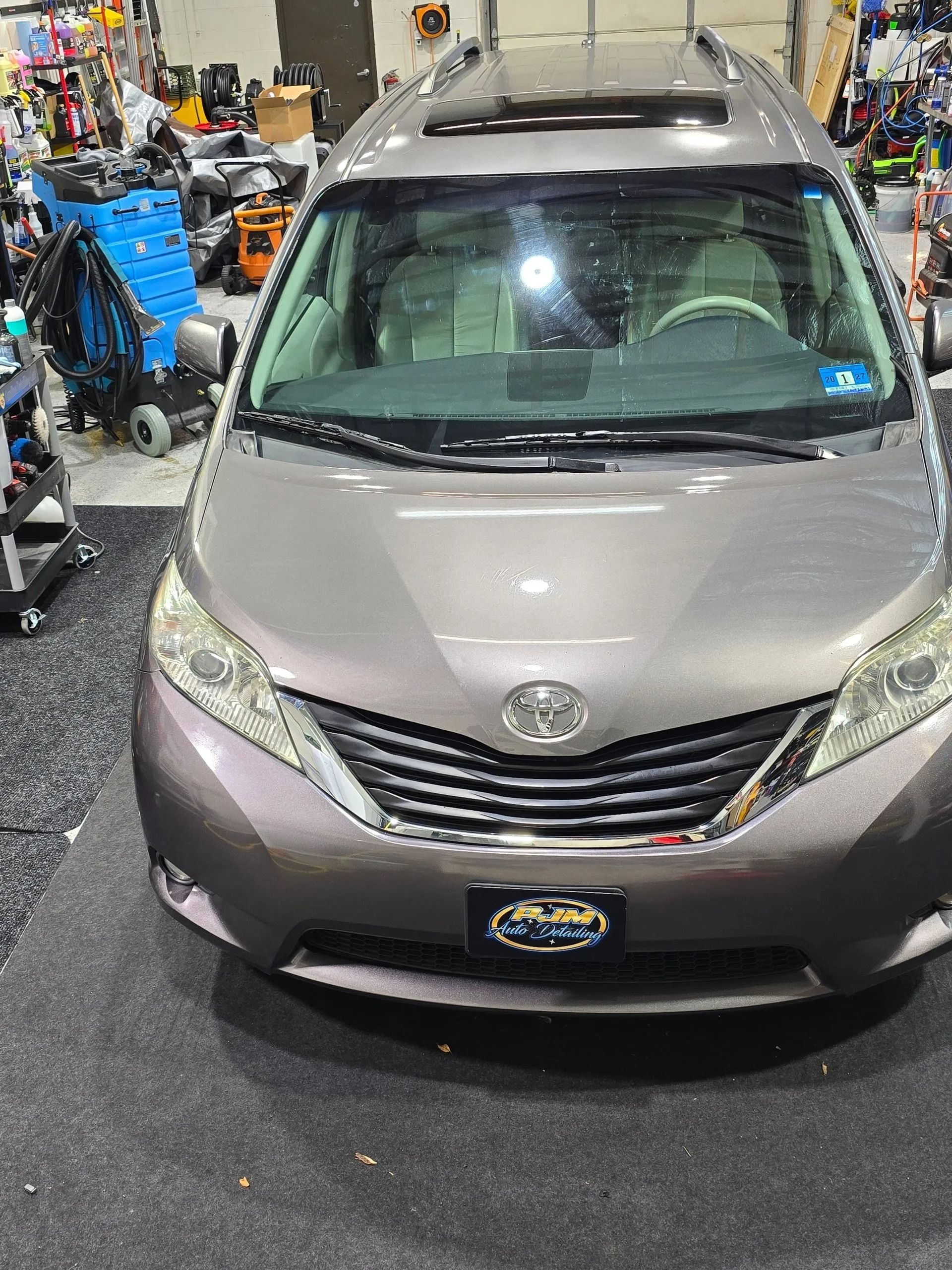 A gray Toyota Sienna minivan parked inside a garage, viewed from the front.
