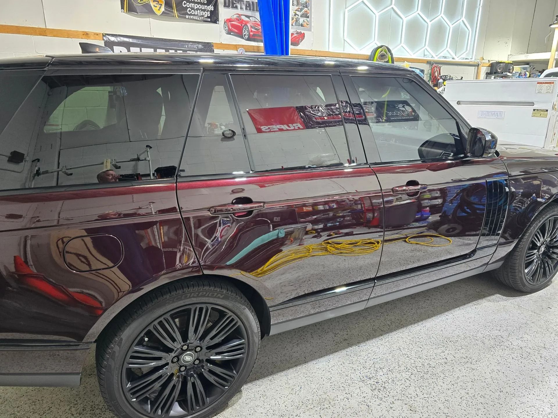 A dark metallic burgundy SUV parked inside a garage with black multi-spoke wheels and tinted windows.