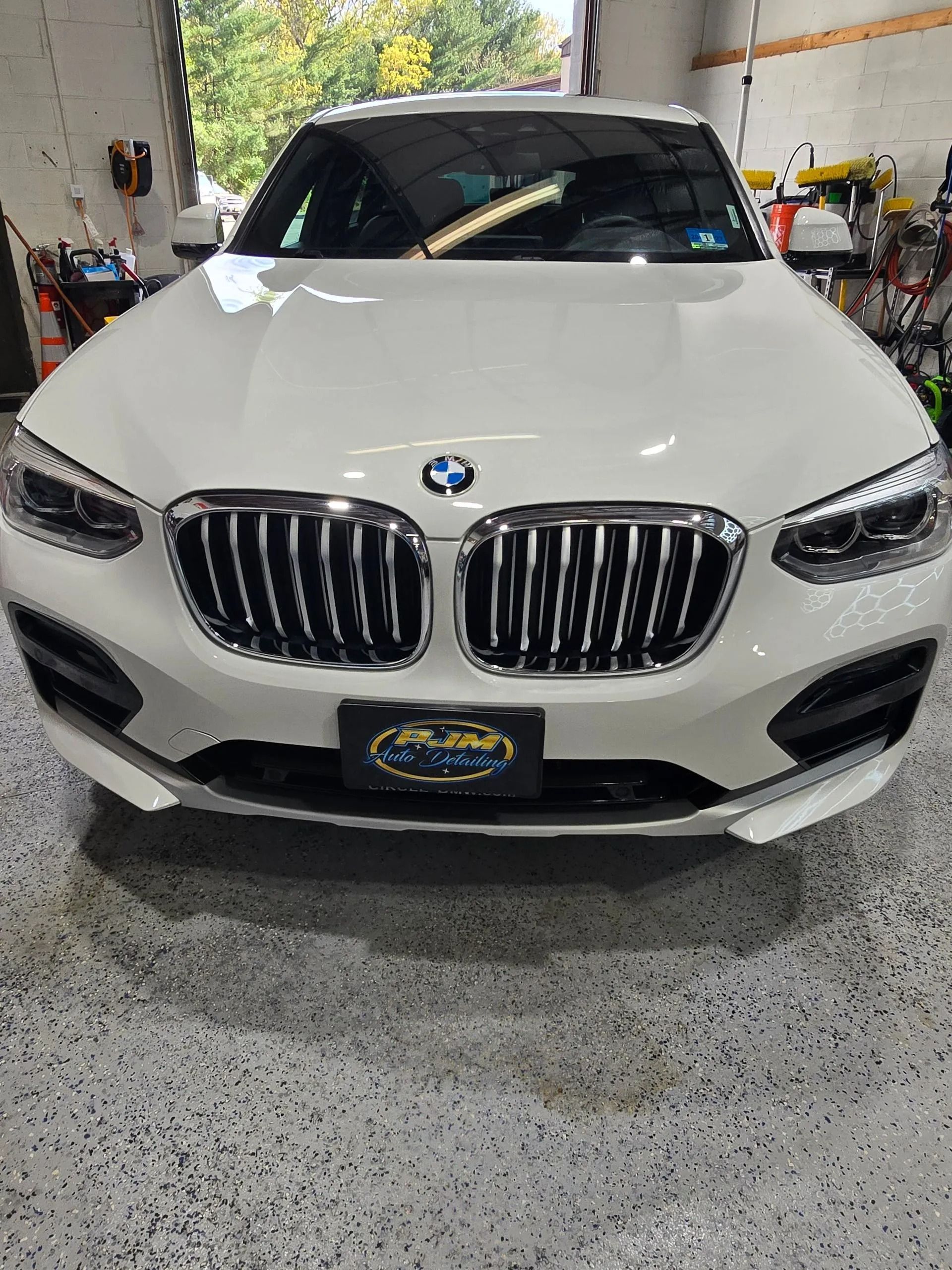 A white BMW SUV parked inside a workshop with a concrete floor.