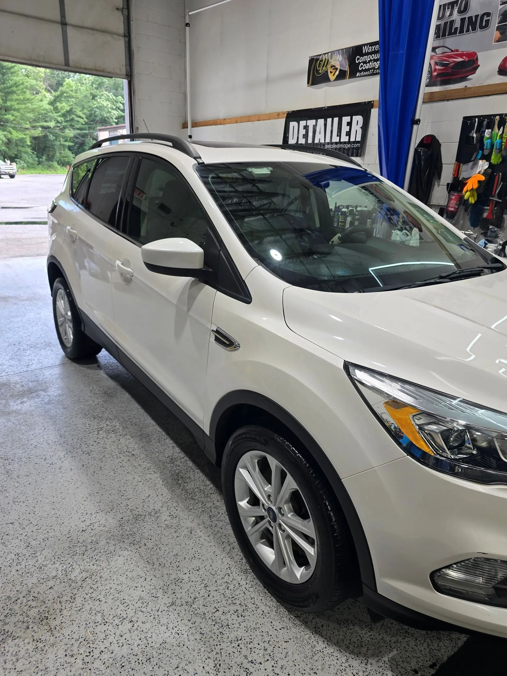 A white Ford Escape SUV parked inside a garage, viewed from the front passenger side.