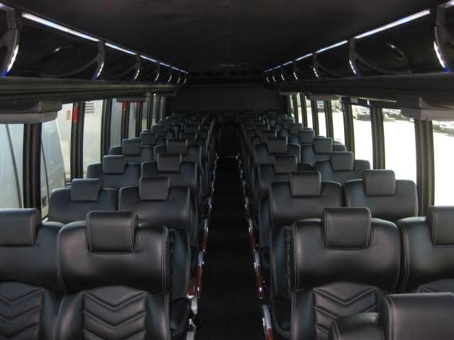 Empty bus interior with rows of black seats and overhead lighting