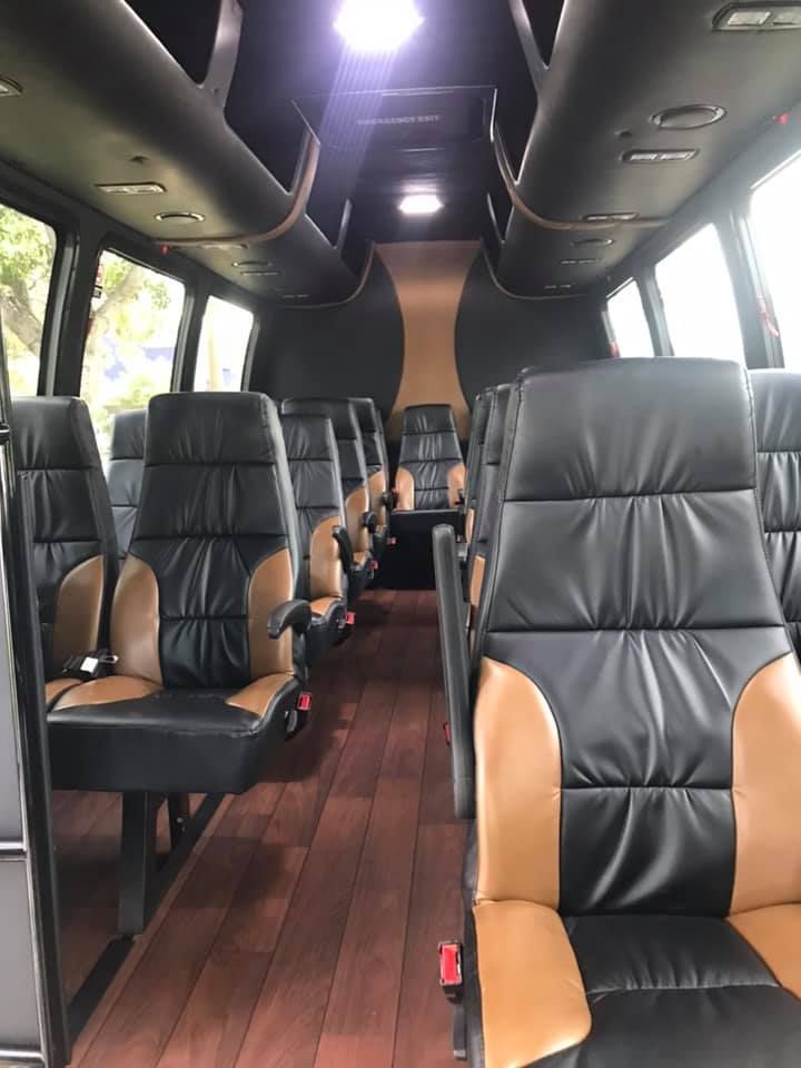 Empty luxury minibus interior with black and tan leather seats and wood-look floor