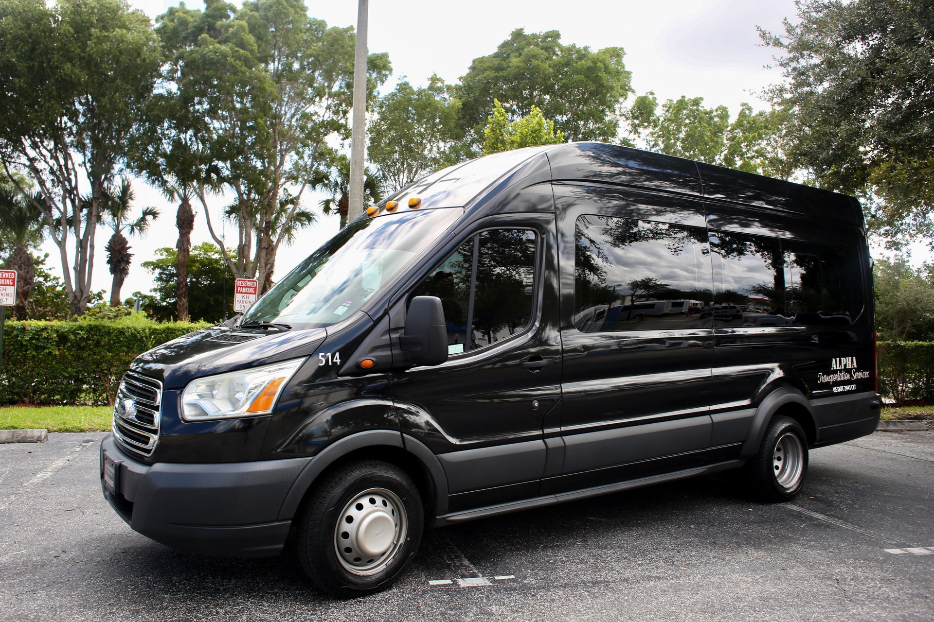 Black passenger van parked on a wet street with trees in the background