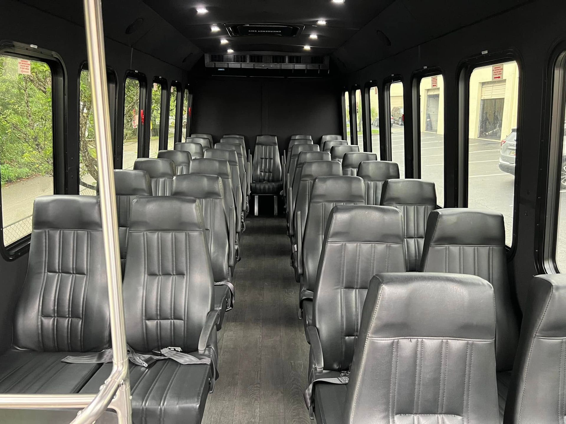 Interior of an empty black passenger shuttle bus with rows of gray seats and large windows
